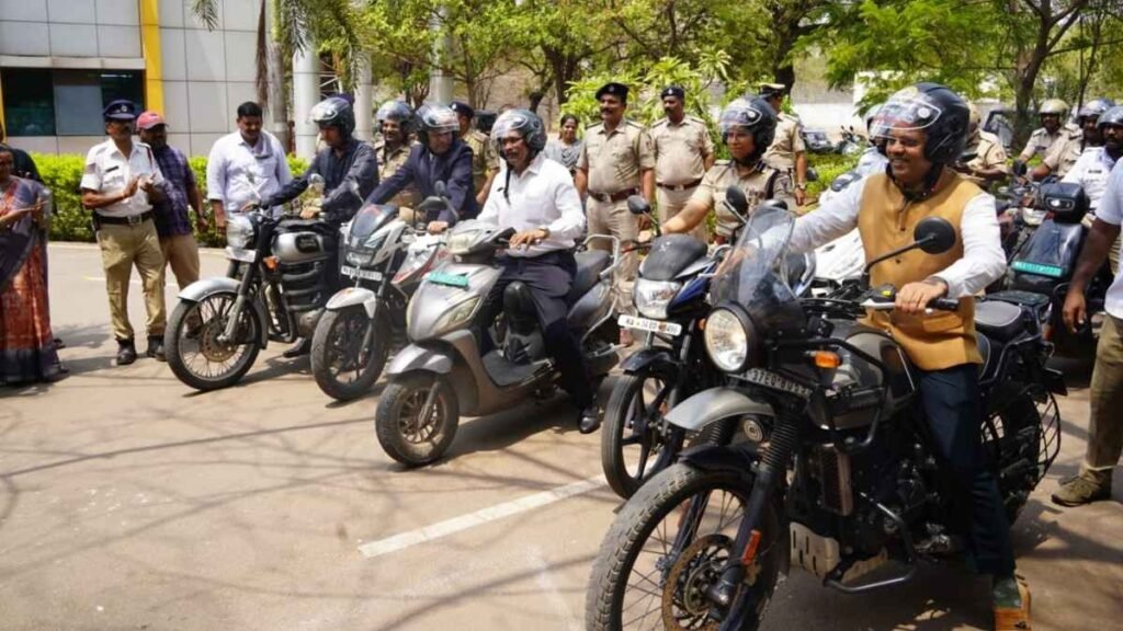 Ballari District Collector Nagendra Prasad riding a motorcycle wearing a helmet during a road safety awareness rally in Ballari city